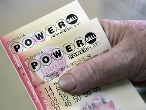 In this Aug. 18, 2017, file photo, a customer shows his Powerball tickets in Hialeah, Fla. (AP Photo/Alan Diaz, File)