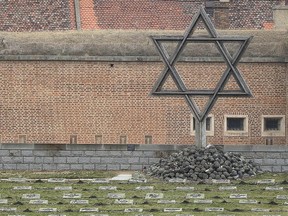 Visitors walk past the star of David at the cemetery of the former Nazi concentration camp in Terezin, Czech Republic, Thursday, Jan. 24, 2019. (AP Photo/Petr David Josek)