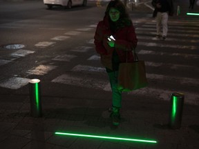 In this Wednesday, March 13, 2019 photo, an Israeli woman walks past embedded LED stoplights at a crosswalk in Tel Aviv, Israel.