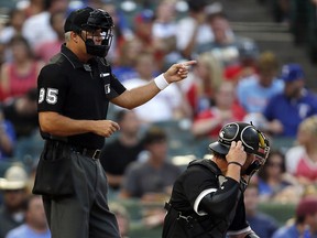 Home plate umpire Tim Timmons (left) signals while Chicago White Sox catcher Kevan Smith, right, adjusts his mask Saturday Aug. 19, 2017, in Arlington, Texas. (AP Photo/Roger Steinman)