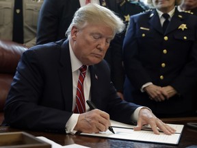 In this March 15, 2019, file photo, President Donald Trump signs the first veto of his presidency in the Oval Office of the White House in Washington. Trump issued the first veto, overruling Congress to protect his emergency declaration for border wall funding.