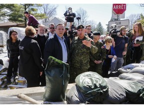 Premier François Legault looks toward the encroaching Rivière des Prairies beside a wall of sand constructed by the Canadian military in Île-Bigras near Montreal on Sunday, April 21, 2019. Legault was touring areas of Laval affected by rising waters. He was accompanied by Laval Mayor Marc Demers and Brigadier-General Jennie Carignan.