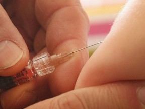 A children's doctor injects a vaccine against measles, rubella, mumps and chicken pox in this file photo.