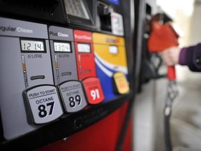 A motorist reaches for the pump at a Toronto gas station. (THE CANADIAN PRESS)