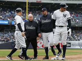 Aaron Judge of the New York Yankees is checked on by bench coach Josh Bard, trainer Steve Donohue and first base coach Reggie Willits prior to leaving a game against the Kansas City Royals at Yankee Stadium on April 20, 2019 in New York City. (Jim McIsaac/Getty Images)