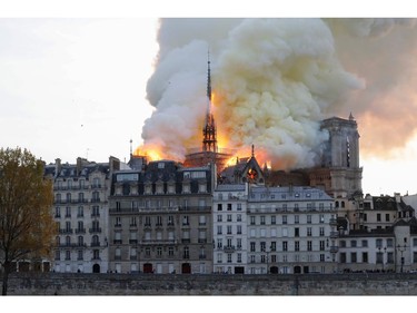 Seen from across the Seine River, smoke and flames rise during a fire at the landmark Notre Dame Cathedral in central Paris on April 15, 2019.