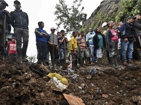 People watch as rescue workers recover a corpse after a landslide in Rosas, Valle del Cauca department, in southwestern Colombia, on April 21, 2019. - At least 14 people were killed and five others injured by a mudslide that buried eight houses early Sunday in southwestern Colombia, authorities said. The national risk management agency attributed the mudslide to the heavy rains that have battered the country for several weeks.
