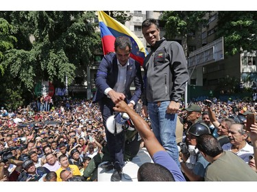 Venezuelan opposition leader and self-proclaimed acting president Juan Guaido (L) and high-profile opposition politician Leopoldo Lopez, who had been put under home arrest by Venezuelan President Nicolas Maduro's regime, greet supporters after being joined by members of the Bolivarian National Guard to oust Maduro, in Caracas on April 30, 2019.
