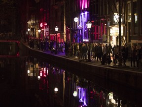 Tourists crowd the narrow canal-side streets in Amsterdam's red light district, Netherlands, Friday evening, March 29, 2019. (AP Photo/Peter Dejong)