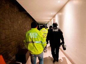 This Friday, April 12, 2019 handout photo provided by the State Attorney General's Office, shows police entering the apartment building where Swedish programmer Ola Bini was residing in Quito, Ecuador.