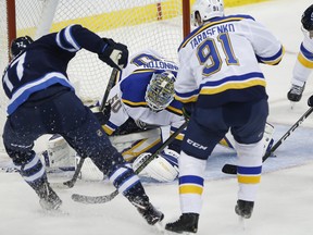 Winnipeg Jets centre Adam Lowry can’t jam the puck under St. Louis Blues goaltender Jordan Binnington last night.