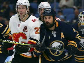 Buffalo Sabres defenseman Zach Bogosian (4) and Calgary Flames forward Sean Monahan (23) battle in front of the net during the second period of an NHL hockey game, Tuesday, Oct. 30, 2018, in Buffalo, N.Y. (AP Photo/Jeffrey T. Barnes)
