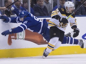 Maple Leafs centre John Tavares (left) dives head-first into the boards while Bruins left wing Brad Marchand skates up ice during third period action in Game 3 of their NHL playoff series in Toronto on Monday, April 15, 2019.