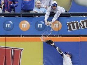 A fan spills beer on Milwaukee Brewers left fielder Ryan Braun as he tries but fails to grab a triple hit by New York Mets' Pete Alonso during the first inning of the MLB baseball game at Citi Field, Sunday, April 28, 2019, in New York.