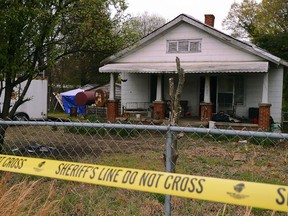 In this Friday, April 5, 2019, photo, police tape marks the area where the Spartanburg County Sheriff's Office and Spartanburg County Coroner's were working after two bodies were found buried on the property on Williams Street in Spartanburg, S.C. Two men have been charged with murder in connection with the discovery.