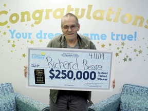 In this Monday, April 1, 2019 photo, made available by North Carolina Education Lottery, Richard Beare holds a large check after winning $250,000 in the North Carolina Education Lottery in Charlotte, N.C. Bears has stage 4 liver cancer and plans to use the money on a trip to Italy with his wife. (North Carolina Education Lottery via AP) ORG XMIT: MH102