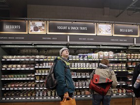 In this Jan. 22, 2018, file photo, a customer looks overhead in an Amazon Go store, where sensors and cameras are part of a system used to tell what people have purchased and charge their Amazon account in Seattle. (AP Photo/Elaine Thompson, File)