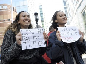 Mackenzie Thomas and Vivi Bonomie hold signs while actress Lori Loughlin faces charges for allegedly conspiring to commit mail fraud and other charges in the college admissions scandal at the John Joseph Moakley United States Courthouse in Boston on April 3, 2019.