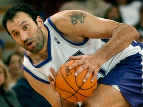 In this Nov. 30, 2003, file photo, Sacramento Kings centre Vlade Divac fights to keep his balance after New Jersey Nets forward Kenyon Marton (not seen) tried to steal the ball during the second half of an NBA game in Sacramento, Calif.