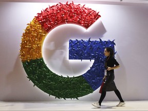 In this Monday, Nov. 5, 2018 file photo, a woman walks past the logo for Google at the China International Import Expo in Shanghai.