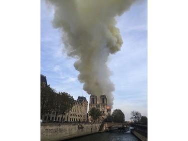 Notre Dame cathedral is burning in Paris, Monday, April 15, 2019. Massive plumes of yellow brown smoke is filling the air above Notre Dame Cathedral and ash is falling on tourists and others around the island that marks the center of Paris.