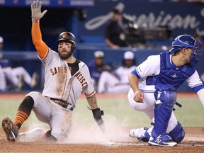 San Francisco Giants’ Kevin Pillar slides across home plate past Blue Jays catcher Luke Maile to score a run in the second inning on Tuesday night at Rogers Centre. Pillar, an ex-Jay, went 1-for-4 with one RBI in his team’s 7-6 win. (GETTY IMAGES)