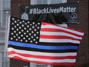 In this July 28, 2016, file photo, a flag with a blue and black stripes in support of law enforcement officers, flies at a protest by police and their supporters outside Somerville City Hall in Somerville, Mass.
