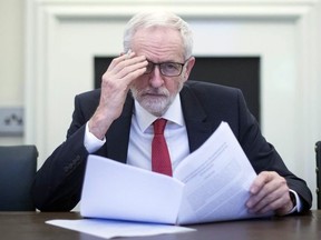 Britain's Labour leader Jeremy Corbyn poses for the media with the Political Declaration setting out the framework for the future UK-EU relationship, in his office in the Houses of Parliament in London, Tuesday, April 2, 2019.