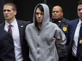 In this Dec. 17, 2015, file photo, Martin Shkreli, the former hedge fund manager under fire for buying a pharmaceutical company and ratcheting up the price of a life-saving drug, is escorted by law enforcement agents in New York, after being taken into custody following a securities probe. Pharmaceutical honcho Shkreli has been banished to solitary confinement amid allegations he was running his drug company from federal prison using a contraband smartphone, a person familiar with the matter told The Associated Press.
