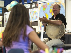 In this 2016 photo, arts teacher John Zeretzke, right, applauds his students after they performed a piece with flutes they built in his class in Lake Forest, Calif.