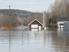 The Darlings Island Road, left, is submerged by the flood waters of the St. John River in Nauwigewauk, New Brunswick, on Friday April 26, 2019.