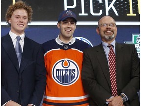 Evan Bouchard, centre, of Canada, poses after being selected by the Edmonton Oilers during the NHL hockey draft in Dallas, Friday, June 22, 2018.