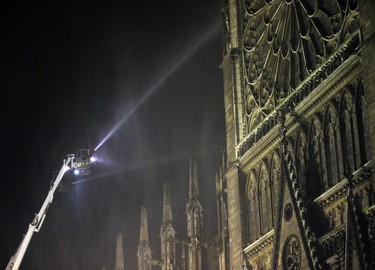 Firefighters spray water onto Notre Dame cathedral as it burns in Paris, Monday, April 15, 2019. Massive plumes of yellow brown smoke is filling the air above Notre Dame Cathedral and ash is falling on tourists and others around the island that marks the center of Paris. (AP Photo/Michel Euler)