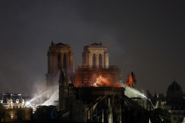 Firefighters tackle the blaze as flames and smoke rise from Notre Dame cathedral as it burns in Paris, Monday, April 15, 2019. Massive plumes of yellow brown smoke is filling the air above Notre Dame Cathedral and ash is falling on tourists and others around the island that marks the center of Paris. (AP Photo/Thibault Camus)