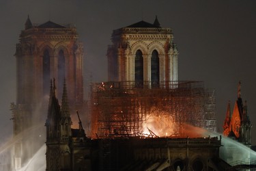 Firefighters tackle the blaze as flames and smoke rise from Notre Dame cathedral as it burns in Paris, Monday, April 15, 2019. Massive plumes of yellow brown smoke is filling the air above Notre Dame Cathedral and ash is falling on tourists and others around the island that marks the center of Paris. (AP Photo/Thibault Camus)