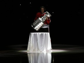 In this Oct. 1, 2013, photo, Blackhawks defenceman Duncan Keith carries out the Stanley Cup during a banner raising ceremony in Chicago. In an Associated Press and Canadian Press survey of player representatives from all 31 NHL teams, 48 percent favor changing the current divisional playoff format.