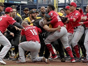 Cincinnati Reds' Yasiel Puig is restrained by Pittsburgh Pirates bench coach Tom Prince, in the middle of a bench clearing brawl during the fourth inning of a baseball game in Pittsburgh, Sunday, April 7, 2019.