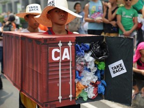 Filipino environmental activists wear mock container vans filled with garbage to symbolize the 50 containers of waste that were shipped from Canada to the Philippines in 2013, as they hold a protest outside the Canadian embassy in the financial district of Makati, south of Manila, Philippines on May 7, 2015.