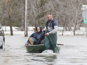 People are pulled in a small boat along a residential street surrounded by floodwaters in the town of Rigaud, Que. west of Montreal, Saturday, April 20, 2019.