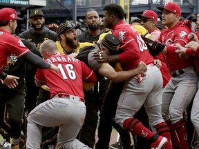 Reds' Yasiel Puig (66) is restrained by Pirates bench coach Tom Prince in the middle of a bench-clearing brawl during the fourth inning of a game in Pittsburgh, Sunday, April 7, 2019.