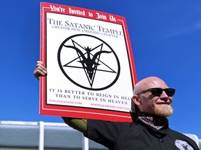 In this Jan. 24, 2015 file photo, Chris Bridges holds a sign for The Satanic Temple during a protest outside of an all-day prayer rally in Baton Rouge. (AP Photo/Jonathan Bachman, File)