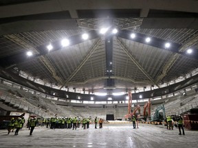 The interior of the existing roof of KeyArena, the only structure that will remain during a major renovation of the building, is visible above what will be the construction site below as media members gather on the floor during a tour of what will be the NHL team site Thursday, April 18, 2019 in Seattle.