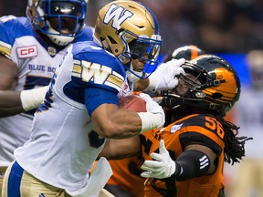 Winnipeg Blue Bombers' Andrew Harris, left, fights off B.C. Lions' Solomon Elimimian as he carries the ball in Vancouver, B.C., on Friday, July 21, 2017. (THE CANADIAN PRESS/Darryl Dyck)