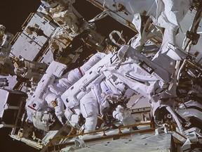 Canadian astronaut David Saint-Jacques, front, and U.S. astronaut Anne McClain take part in a spacewalk as seen in the livefeed from the Canadian Space Agency headquarters Monday, April 8, 2019 in St. Hubert, Que.