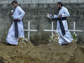 Fathers from local church pass the graves after the mass funeral in Katuwapity village on April 23, 2019 in Negambo, Sri Lanka. (Atul Loke/Getty Images)