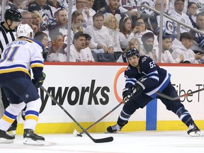 WINNIPEG, MANITOBA - APRIL 10: Mark Scheifele #55 of the Winnipeg Jets tries to move the puck past Ryan O'Reilly #90 and Vladimir Tarasenko #91 of the St. Louis Blues in Game One of the Western Conference First Round during the 2019 NHL Stanley Cup Playoffs at Bell MTS Place on April 10, 2019 in Winnipeg, Manitoba, Canada. (Photo by Jason Halstead/Getty Images)