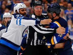 Linesman Ryan Gibbons restrains Brayden Schenn of the St. Louis Blues and Dustin Byfuglien of the Winnipeg Jets (left) in Game 3 of the Western Conference First Round during the 2019 NHL Stanley Cup Playoffs on Sunday in St. Louis.