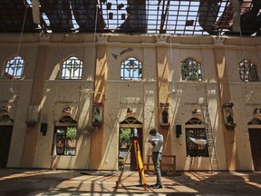 In this Thursday, April 25, 2019 photo, sunlight steams in from gaping holes, as a surveyor works at St. Sebastian's Church, in Negombo, Sri Lanka.