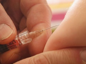 A children's doctor injects a vaccine against measles, rubella, mumps and chicken pox in this file photo.