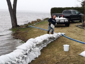 Terry Lance places sandbags at his Cedar Lane home Thursday afternoon after picking up a trailer full at the sandbag filling station at the Pembroke and Area Community Centre. This is the highest he has ever seen the Ottawa River.